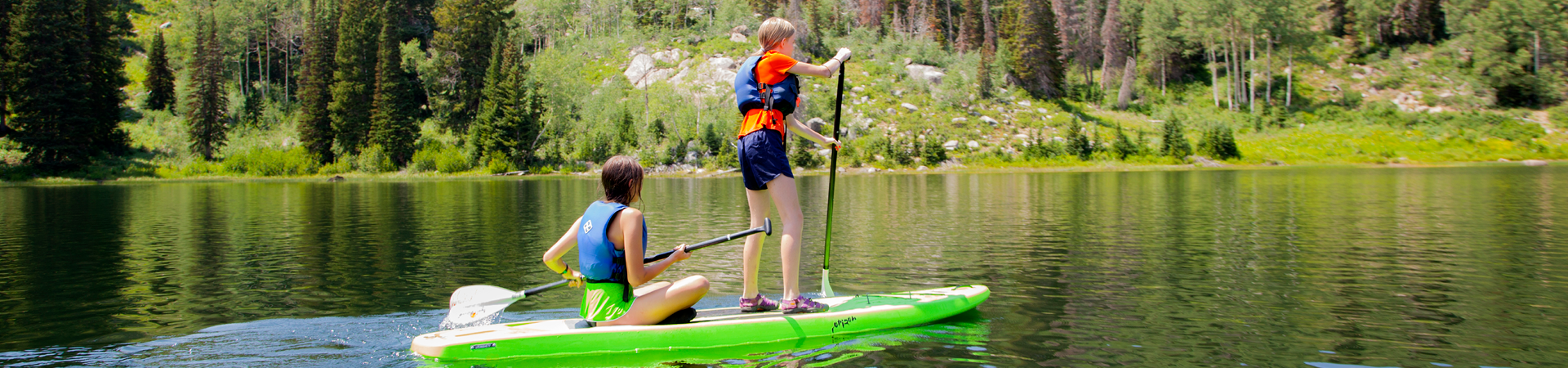 Two Girl Scouts on a paddle board in a lake
